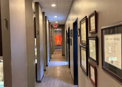Hallway inside Better Life Dental Implant Center with treatment rooms and framed dental certificates